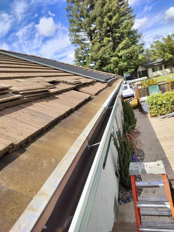 New white gutter installation featuring a part of a ladder.
