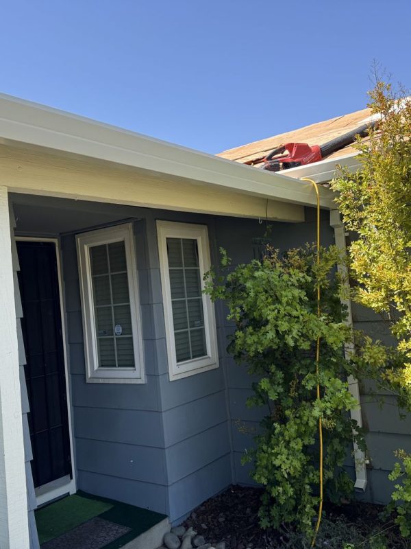 Front side of the home. Gutters are installed. This is featuring a bush that is planted along side the right side of the front of the home
