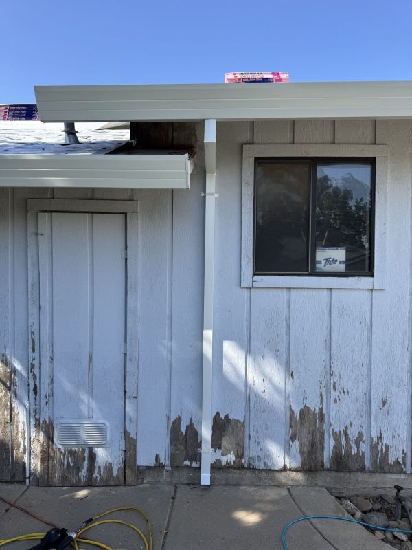 White Downspout placed next to a square window.