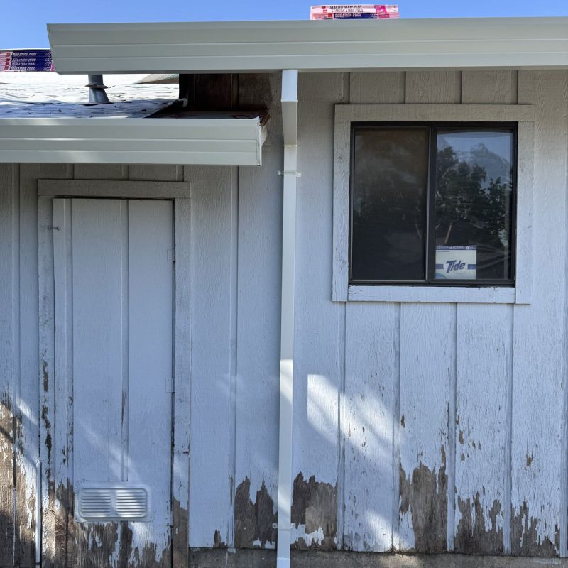 White Downspout placed next to a square window.