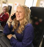 Office assistant in gutter office taking a call to schedule for an estimate